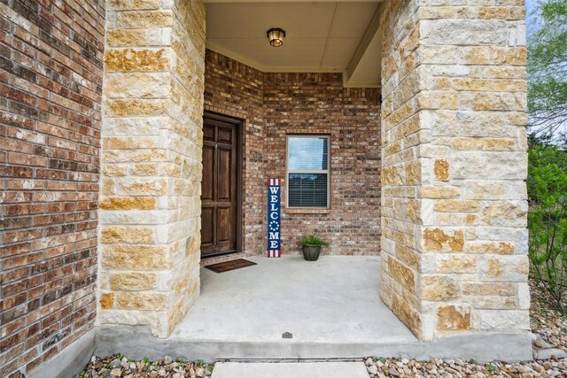 property entrance with a porch and brick siding