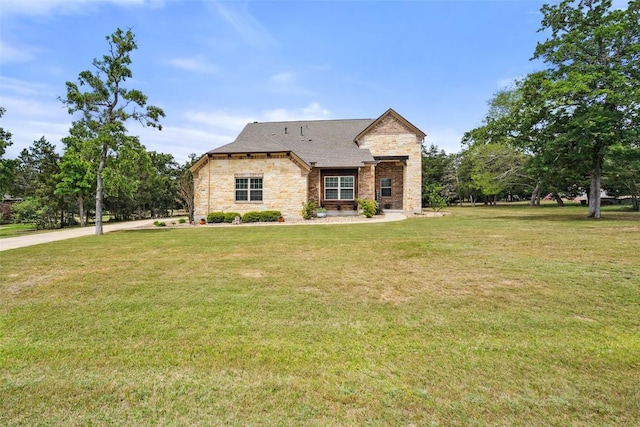 french country style house with stone siding and a front yard