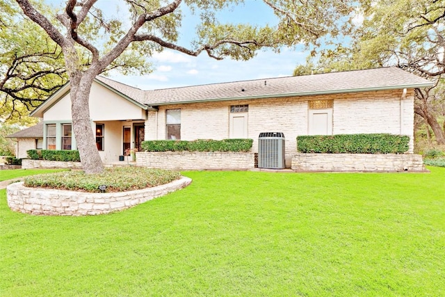 view of front of house with a front yard, brick siding, and central air condition unit