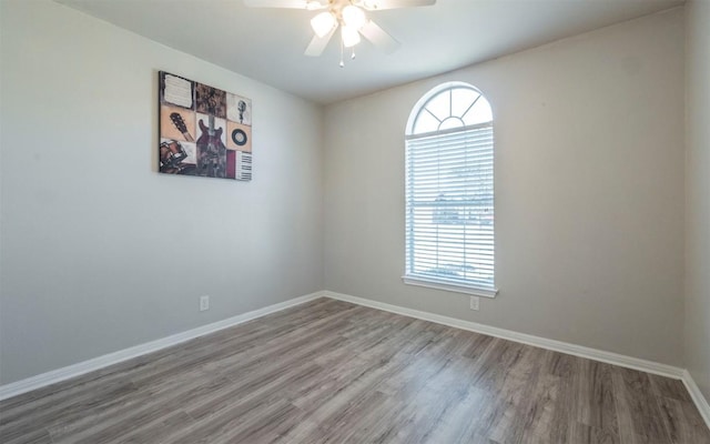 empty room featuring ceiling fan, baseboards, and wood finished floors