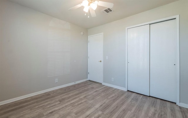 unfurnished bedroom with baseboards, a closet, visible vents, and wood finished floors