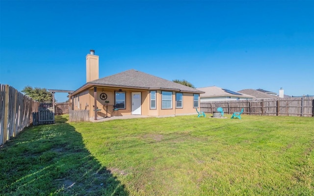 rear view of property with a patio, a fenced backyard, a yard, stucco siding, and a chimney