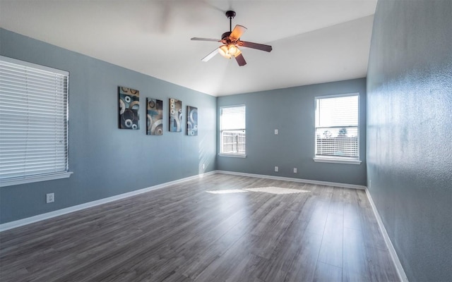 empty room with lofted ceiling, ceiling fan, baseboards, and wood finished floors