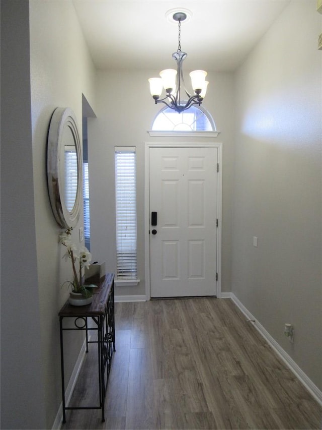 entrance foyer featuring baseboards, wood finished floors, and a notable chandelier