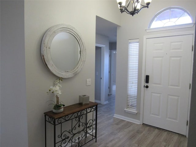 foyer featuring a chandelier, baseboards, and wood finished floors