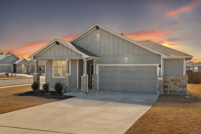 craftsman house featuring driveway, stone siding, board and batten siding, an attached garage, and a shingled roof