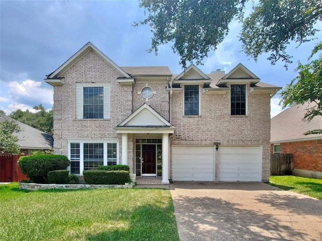 traditional-style house featuring brick siding, concrete driveway, a front yard, fence, and a garage