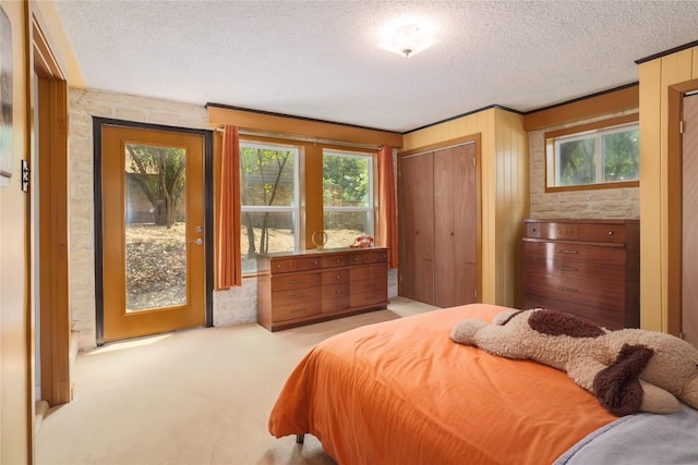 bedroom featuring access to outside, light carpet, and a textured ceiling