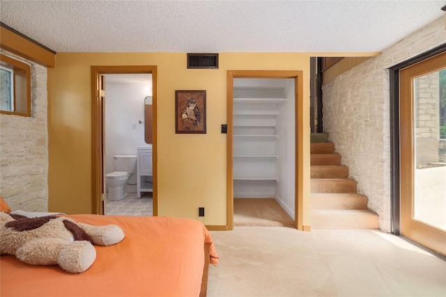 bedroom featuring visible vents, connected bathroom, a spacious closet, a textured ceiling, and carpet floors