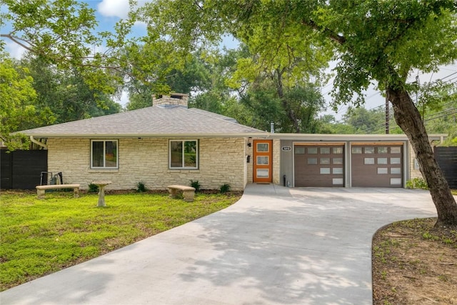 view of front of house featuring stone siding, a chimney, concrete driveway, and a front yard