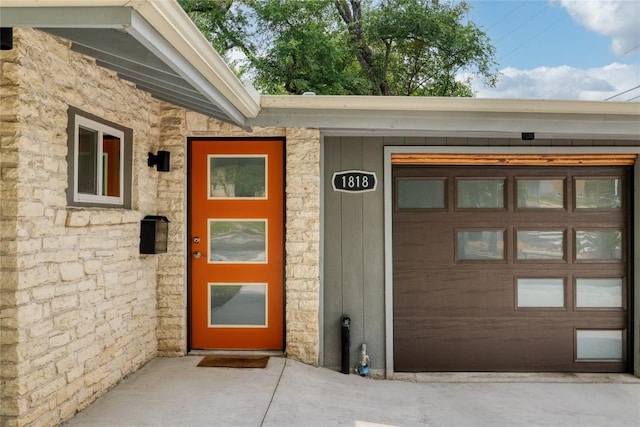 doorway to property with a garage and stone siding