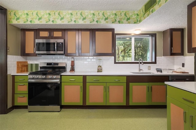 kitchen with stainless steel appliances, light countertops, a sink, and green cabinets