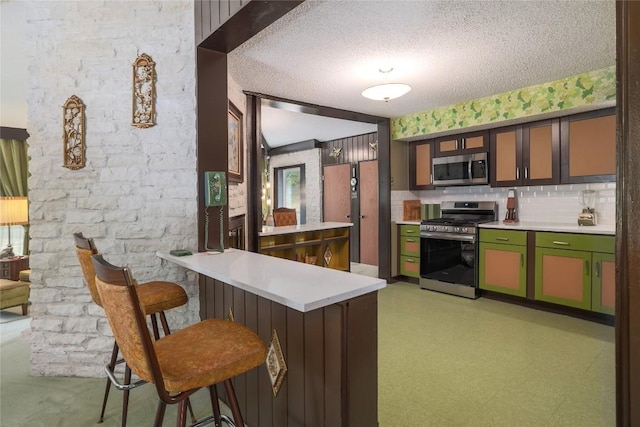 kitchen featuring light floors, stainless steel appliances, light countertops, a textured ceiling, and a peninsula