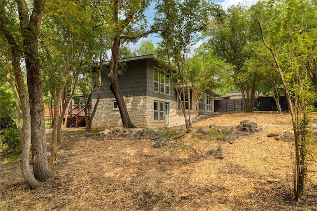 exterior space featuring stone siding and fence