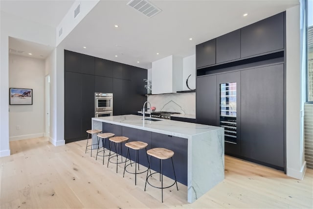 kitchen with stainless steel appliances, dark cabinetry, backsplash, modern cabinets, and a kitchen bar