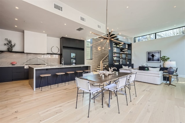 dining area with light wood-style floors, stairs, visible vents, and an inviting chandelier