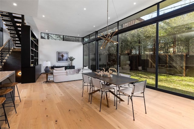 dining room with recessed lighting, floor to ceiling windows, hardwood / wood-style floors, and stairs