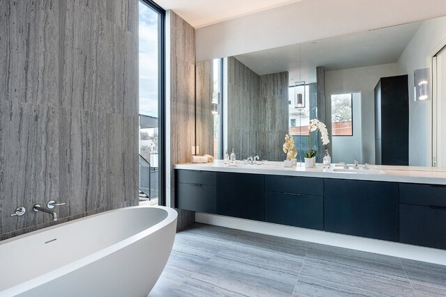 full bath with double vanity, a soaking tub, floor to ceiling windows, and a sink