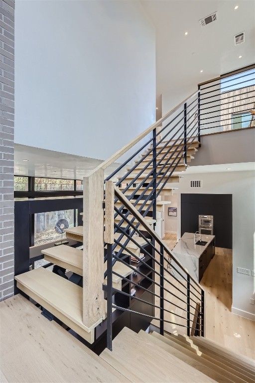 stairway with recessed lighting, visible vents, and wood finished floors