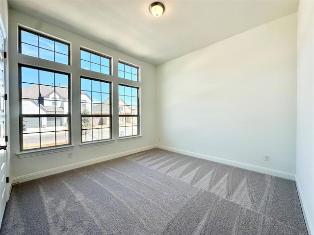 carpeted empty room featuring baseboards