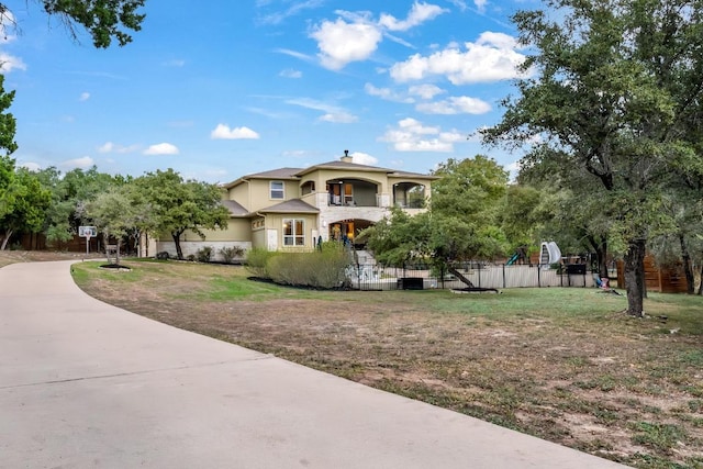 mediterranean / spanish-style house featuring a front yard, fence, and stucco siding