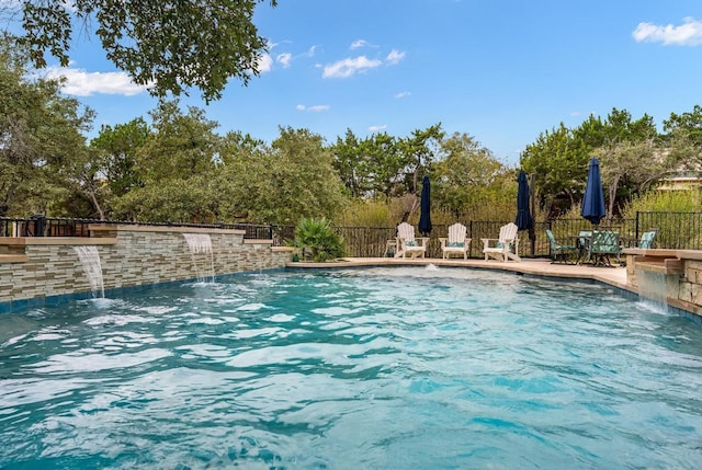 pool with a patio area and fence