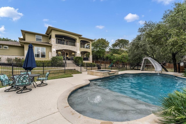 view of swimming pool featuring a patio area, a fenced backyard, a pool with connected hot tub, and a water slide