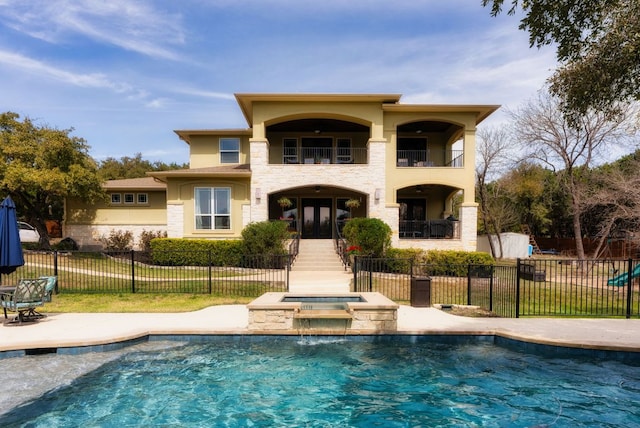 back of property featuring stucco siding, a patio, fence, french doors, and a balcony