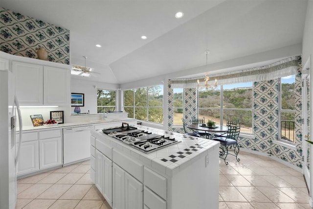 kitchen featuring tile countertops, lofted ceiling, white appliances, white cabinets, and wallpapered walls