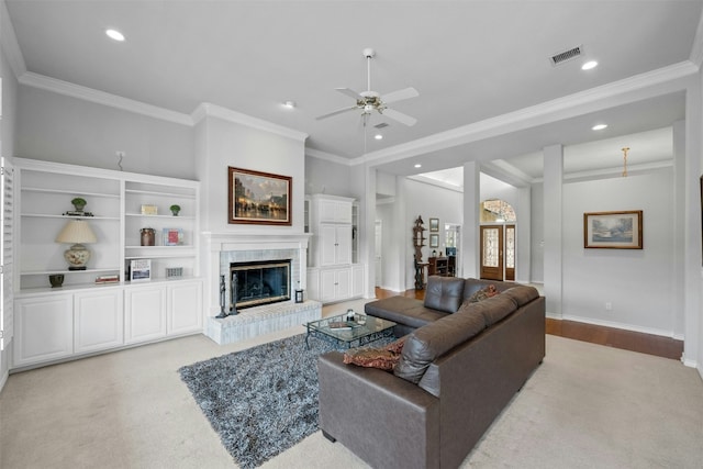 living room with recessed lighting, visible vents, ornamental molding, and a glass covered fireplace