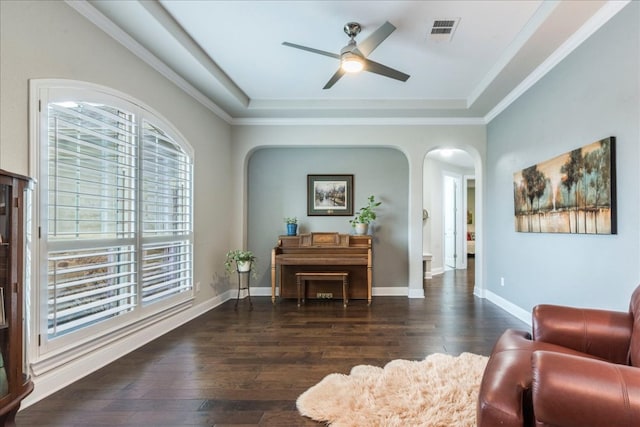 sitting room with arched walkways, wood-type flooring, visible vents, and baseboards