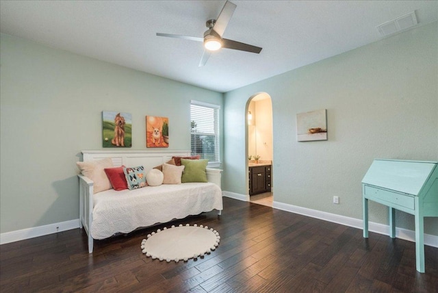 bedroom with arched walkways, connected bathroom, wood finished floors, visible vents, and baseboards