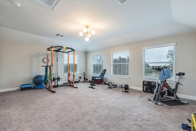 exercise room featuring carpet floors, visible vents, a notable chandelier, and baseboards