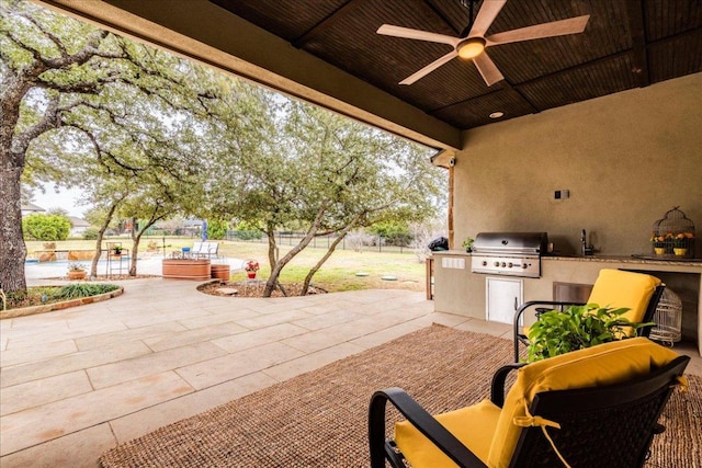 view of patio featuring area for grilling, a sink, ceiling fan, fence, and exterior kitchen