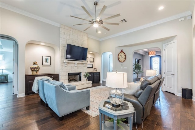 living area with a stone fireplace, ornamental molding, dark wood-style flooring, and baseboards