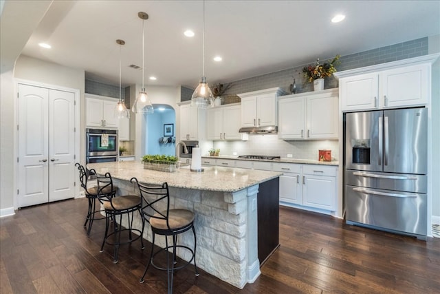 kitchen with stainless steel appliances, white cabinets, under cabinet range hood, and dark wood-style floors