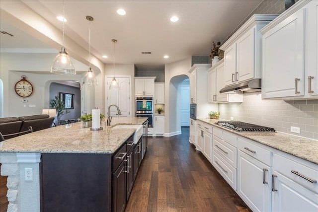 kitchen featuring arched walkways, under cabinet range hood, white cabinetry, visible vents, and appliances with stainless steel finishes