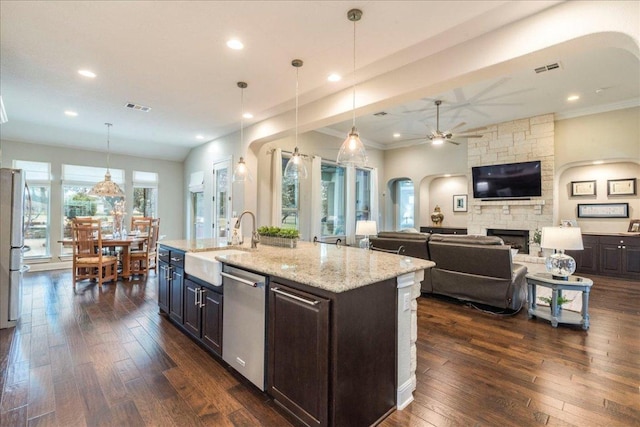 kitchen featuring visible vents, dishwasher, dark wood-type flooring, a fireplace, and a sink