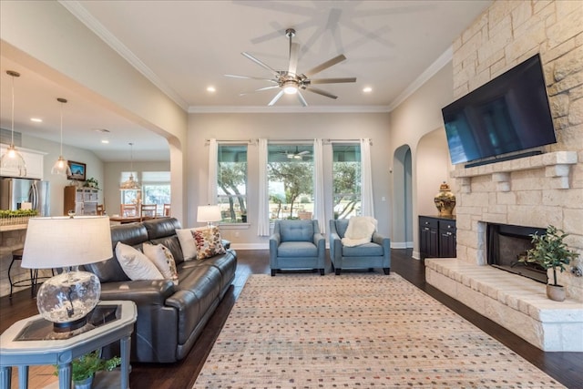 living room featuring ornamental molding, a fireplace, baseboards, and wood finished floors