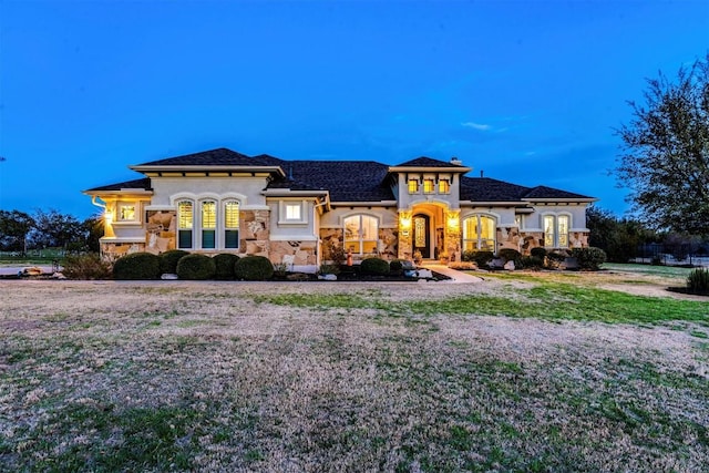 mediterranean / spanish-style home with stone siding, a front lawn, and stucco siding