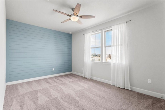 carpeted empty room featuring a ceiling fan and baseboards