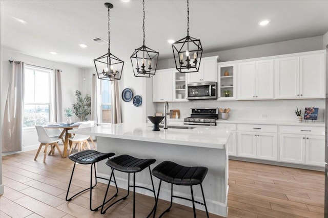 kitchen featuring a breakfast bar, light wood-style floors, tasteful backsplash, and stainless steel appliances