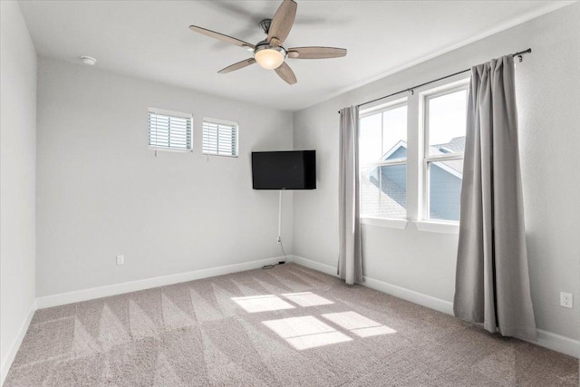 carpeted empty room with ceiling fan and baseboards