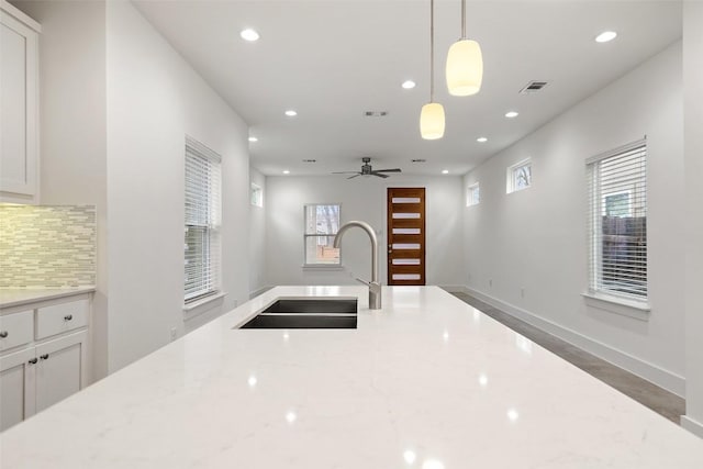 kitchen with a sink, light stone countertops, and decorative backsplash