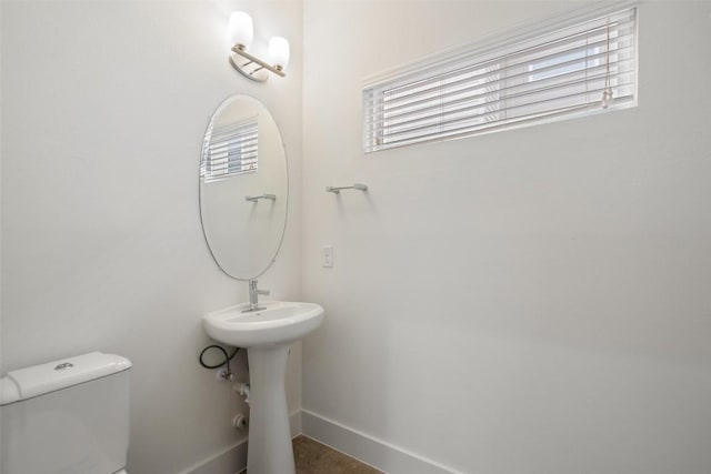 half bathroom featuring baseboards and toilet