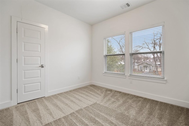 spare room featuring carpet flooring, visible vents, and baseboards