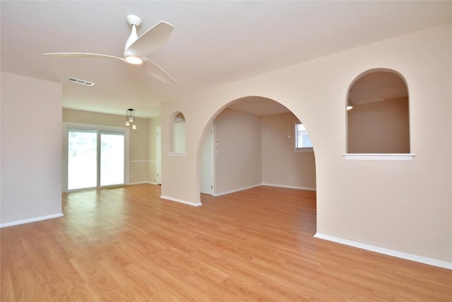 unfurnished room with ceiling fan, light wood-style flooring, a wealth of natural light, and visible vents