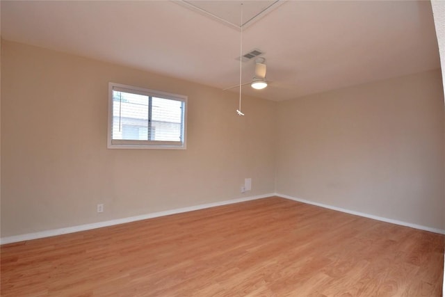 unfurnished room featuring attic access, baseboards, visible vents, and light wood finished floors