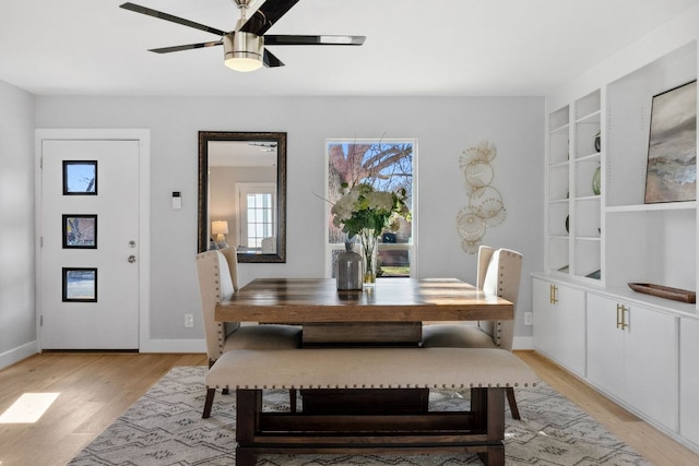 dining space featuring light wood-type flooring, baseboards, and a ceiling fan