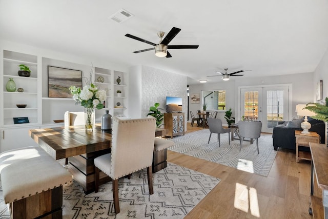 dining room with visible vents, ceiling fan, french doors, light wood-style floors, and built in shelves